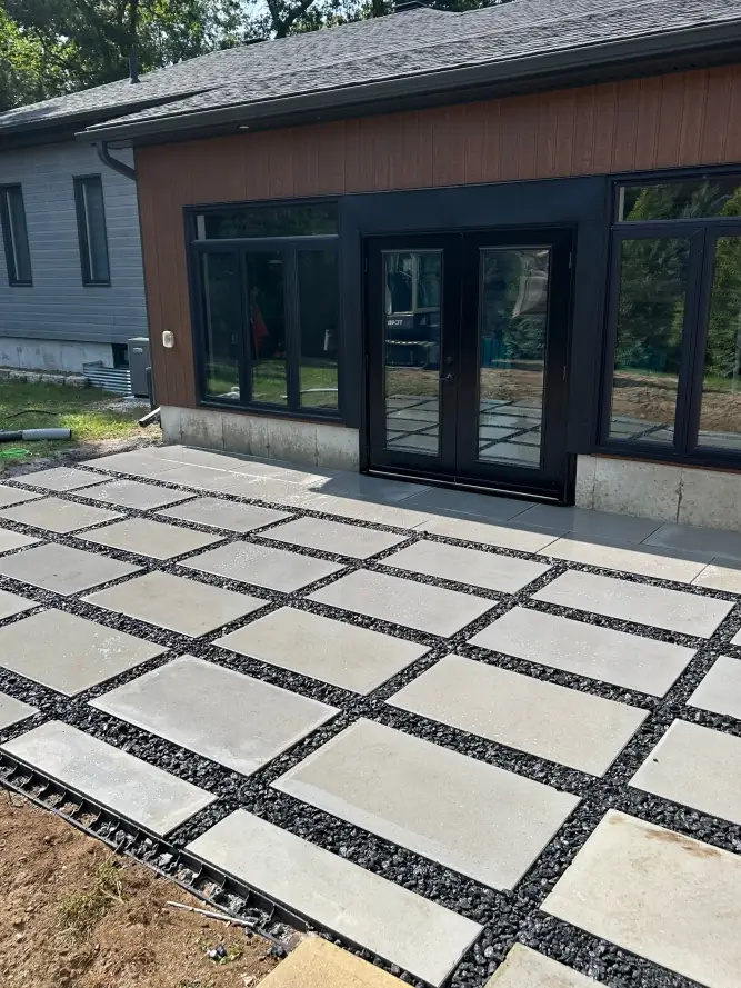 Modern stone slab patio with black gravel joints installed by Armour Designs for a contemporary backyard.
