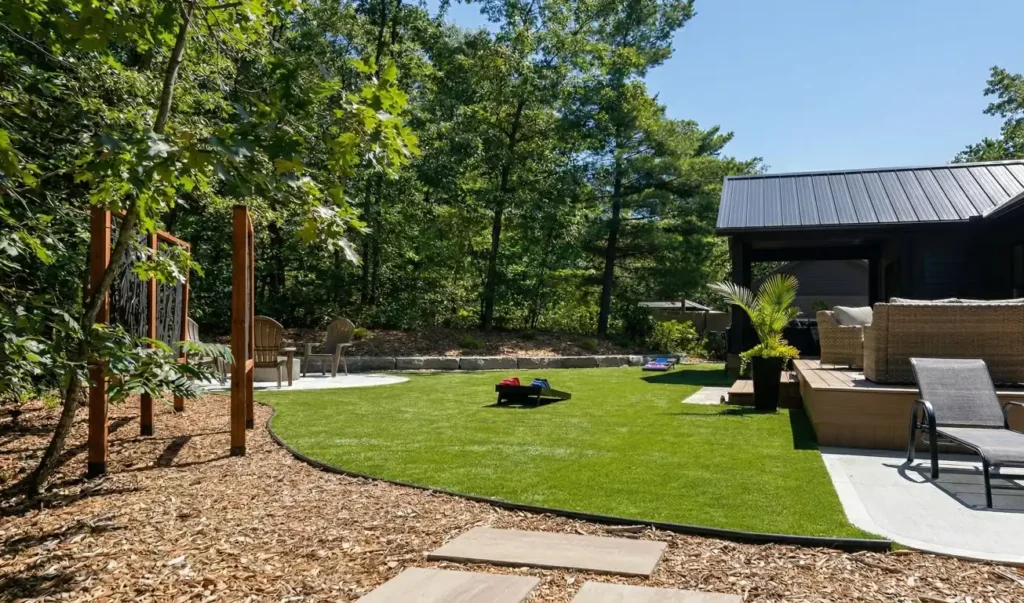 Backyard landscaping with artificial turf, patio seating area, and outdoor living space in a rural Ontario home